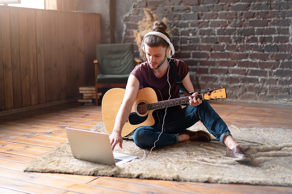 Musician on the floor with a guitar writing music